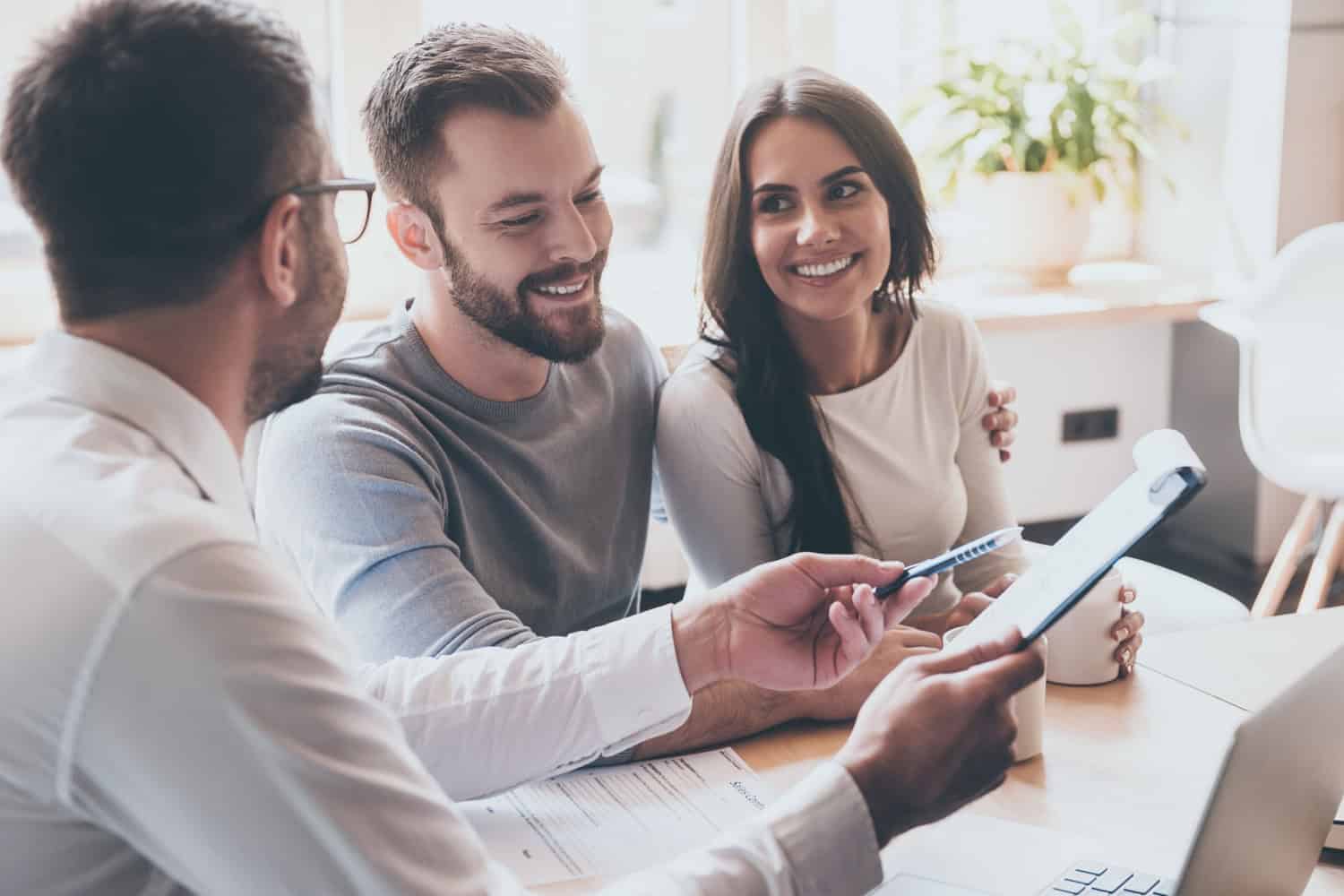A financial advisor showing a notepad to two clients.
